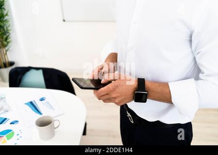 Midsection of male entrepreneur using smart phone at creative office Stock Photo