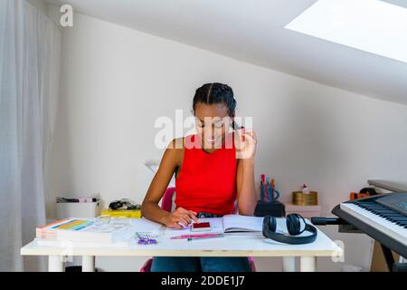 Teenage girl text messaging on smart phone while sitting at home Stock Photo