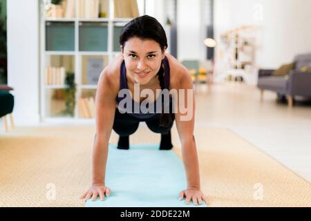 Young woman doing push ups at home Stock Photo