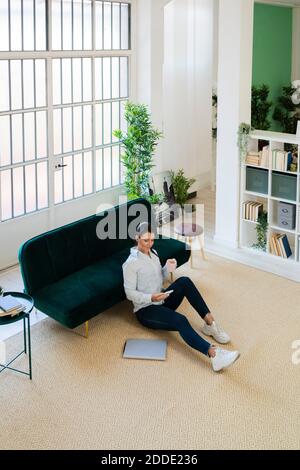 High angle view of woman using smart phone while drinking coffee at home Stock Photo