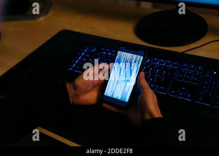 Hacker using mobile phone for coding while working at office Stock Photo