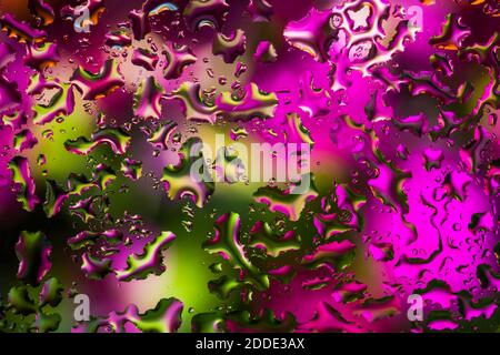 Water drops on glass with colorful background, abstract rainy wallpaper Stock Photo