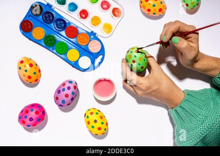 Hands of woman painting Easter eggs with colorful watercolors Stock Photo
