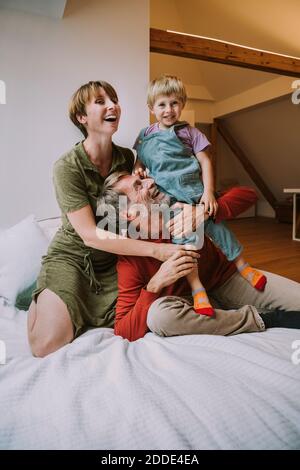 Mother and father embracing son while sitting on bed at home Stock Photo