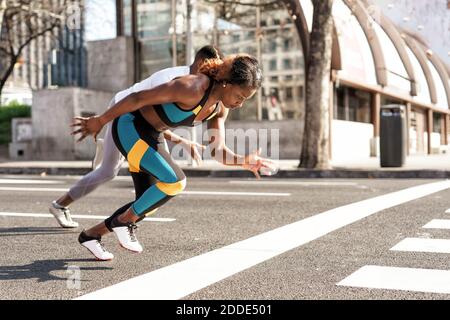 Young man and woman practicing for sports race while running in city Stock Photo