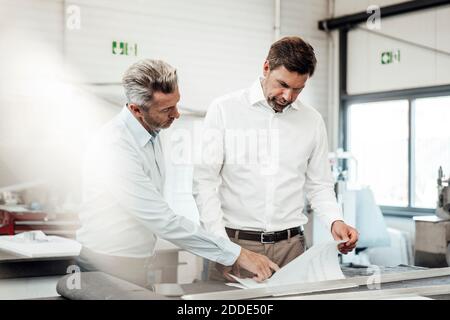 Male engineers planning over document at workbench in industry Stock Photo