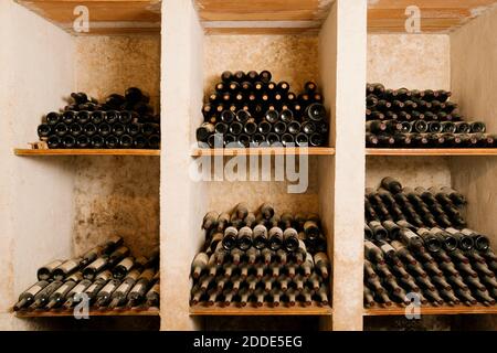 Stack of old wine bottles in rack at cellar Stock Photo