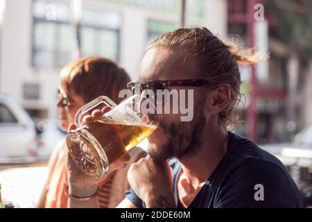 Mid adult man drinking beer while sitting in cafe Stock Photo