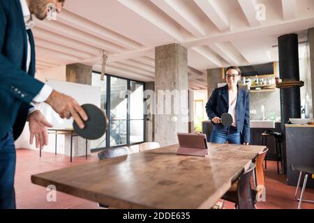 Business people playing table tennis while standing at office Stock Photo