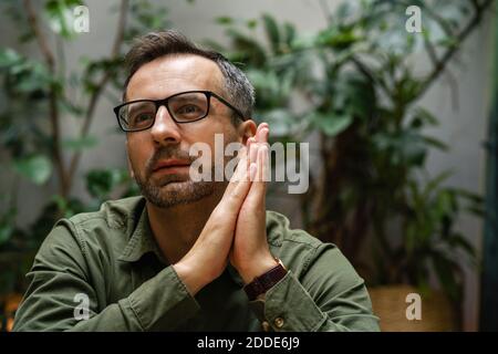 Thoughtful businessman sitting with hands clasped at cafe Stock Photo