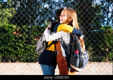 Brother and sister embracing each other while standing in public park on sunny day Stock Photo