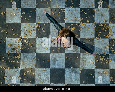 Carefree woman spinning on asphalt painted with checked pattern Stock Photo
