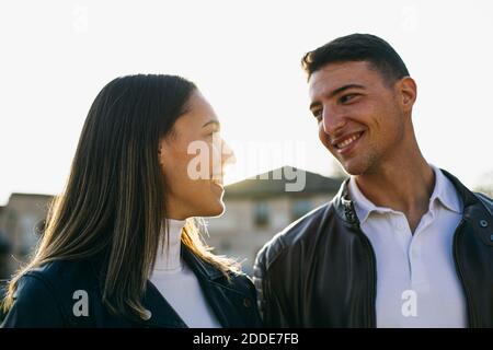 Couple smiling while looking at each other outdoors Stock Photo