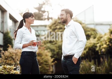 Smiling male and female colleagues talking while taking break at industry Stock Photo