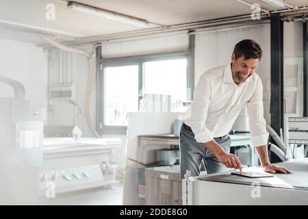 Smiling engineer using digital tablet in factory Stock Photo