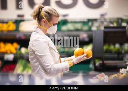 Teenage girl wearing protectice mask and gloves choosing fruits at supermarket Stock Photo