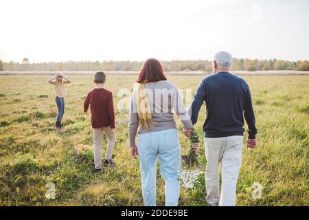 Grandparents spending time with grandchildren on field during weekend Stock Photo