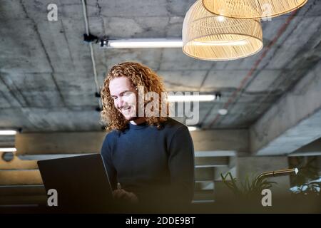 Smiling redhead man using laptop at home Stock Photo