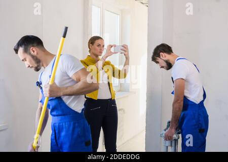 Construction team doing repairs. Two men use a roller and mixer Stock Photo