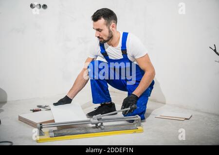 The repairer measures the tiles and cuts them with a ceramic saw Stock Photo