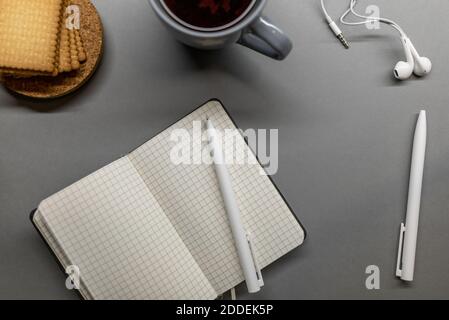 open notebook cup cookie and pens on grey table Stock Photo