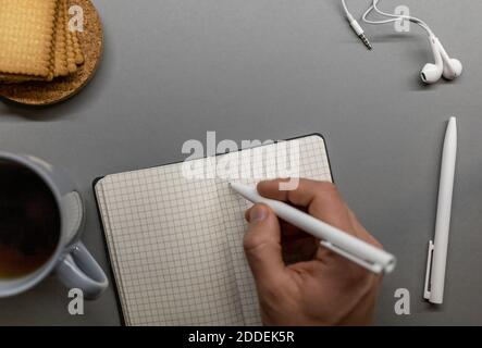 open notebook cup cookie and pens on grey table Stock Photo