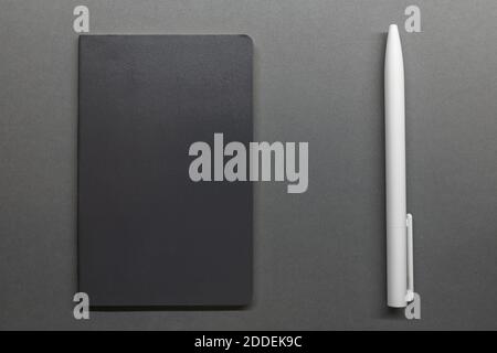 grey notebook and white pen on table flat lay Stock Photo