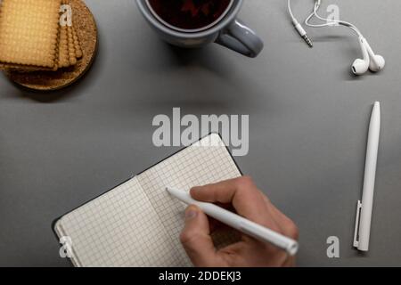 open notebook cup cookie and pens on grey table Stock Photo