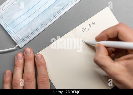 open notebook and face mask hand writing plan Stock Photo