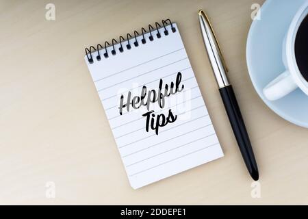 HELPFUL TIPS text with fountain pen and cup of coffee on wooden background. Business and copy space concept. Stock Photo