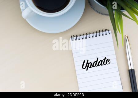 UPDATE text with fountain pen, notepad, decorative flower and cup of coffee on wooden background. Business and copy space concept. Stock Photo