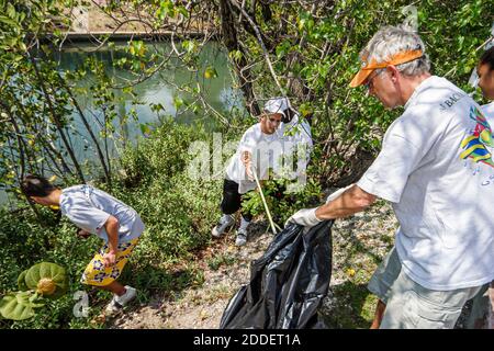 Miami Beach Florida,Dade Canal teenagers teens students,Job Corps workers volunteers cleaning collecting collect trash,boys senior man plastic bag rea Stock Photo