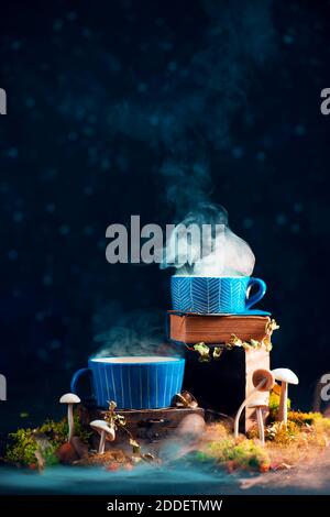 Magical potion in ceramic cups with rising steam and mushrooms Stock Photo