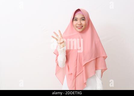 A portrait of happy asian muslim woman wearing a veil or hijab showing and pointing up with fingers number three while smiling confident. Isolated on Stock Photo