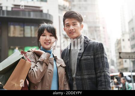 outdoor portrait of happy young asian couple carrying shopping bags Stock Photo