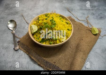 Popular breakfast item Poha or flattened rice in a bowl on a background. Stock Photo