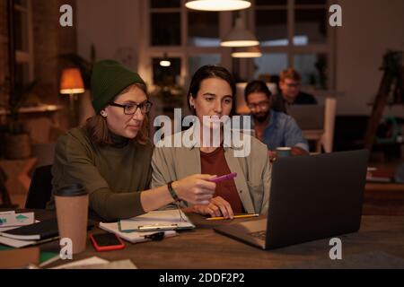 Two designers sitting at the table and using laptop at work they working in team at office Stock Photo