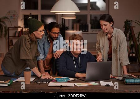 Group of designers using laptop together at the table making online presentation in team at office Stock Photo
