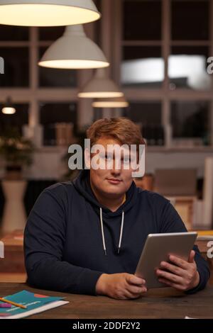 Portrait of young businessman in casual clothing looking at camera while working on digital tablet Stock Photo