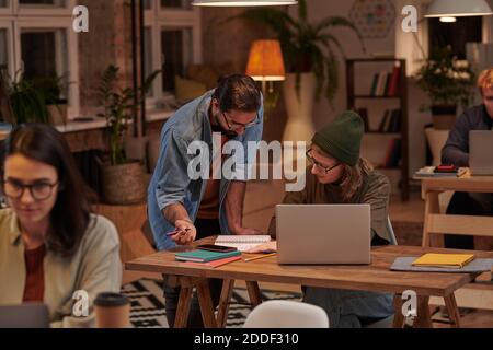 Two designers discussing project together working with their notes and laptop at office Stock Photo