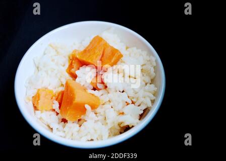 Seasoned steam rice with sweet potato, East Asian Sweet Potato Rice on black background. Copy Space Stock Photo