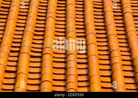 A perspective view of rows of old rustic terracotta roof tiles typical of those found on older traditional buildings in Asia and the Mediterranean. Stock Photo