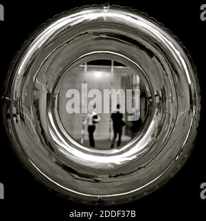 A blurred image of office workers viewed through a shiny stainless steel ring. Stock Photo