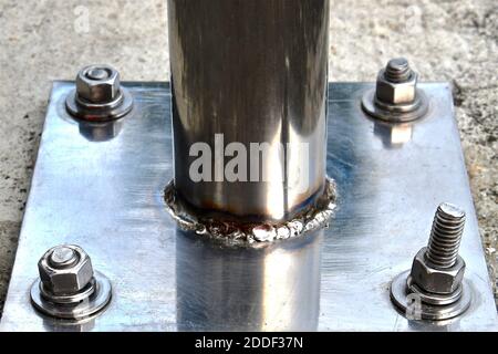 Side perspective view of a stainless steel plate with industrial size nuts and bolts. Stock Photo