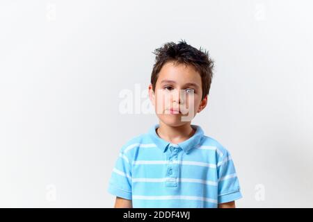 The boy in a blue T-shirt with a brooding face looks somewhere from the side. Stock Photo