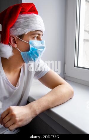 Pensive Young Man in Santa Hat by the Window Stock Photo