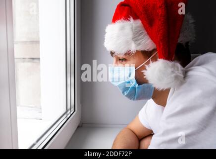 Pensive Young Man in Santa Hat by the Window Stock Photo