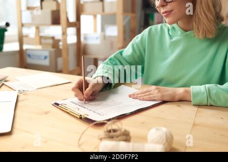 Close-up of young woman sitting at the table and writing plans in her document Stock Photo