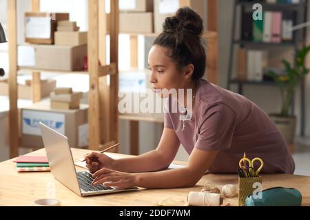 Young woman typing on laptop at the table in workshop Stock Photo