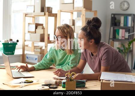 Two fashion designers using laptop to project new design online in workshop Stock Photo